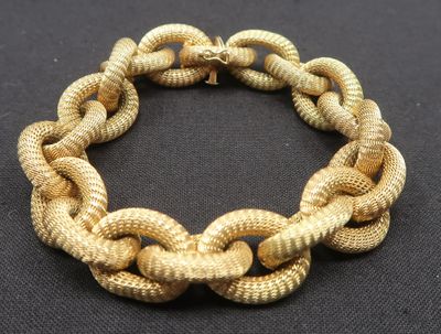 gros plan d'un bracelet en chaîne en or sur une surface noire