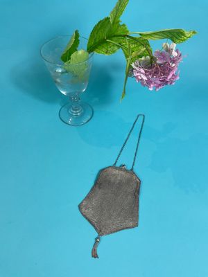 a glass of water and a flower in a vase on a blue table