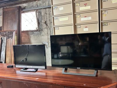 two televisions sitting on top of a wooden table