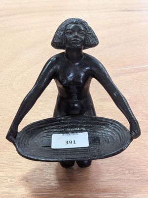 une statue représentant une femme tenant un bol posé sur une table