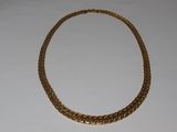 a close up of a gold necklace on a white surface