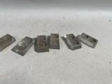 six pièces métalliques sont disposées en ligne sur une surface blanche