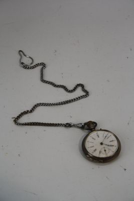 une petite montre de poche attachée à une chaîne, posée sur une table