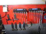 many wrenches hanging on a red wall in a garage