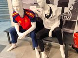 two mannequins sitting on a bench next to each other