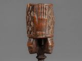 an african carved wooden headdress with two hands on it