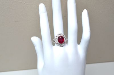a hand with a ring on it that has a red stone in it
