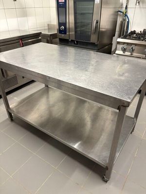 a large stainless steel table in the middle of a kitchen