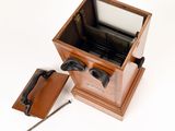a small wooden box with a metal handle and a leather case
