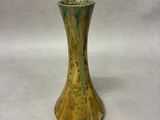 a green and gold vase sitting on a white surface