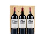 three bottles of red wine in a wooden box on a white surface