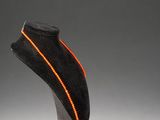 a black and orange necklace on a stand with an orange cord