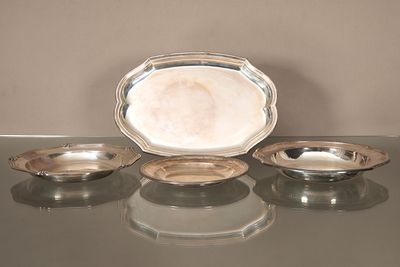 trois plats en argent posés sur une table en verre