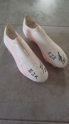 une paire de chaussures avec des inscriptions dessus, posée par terre