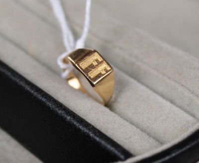 une bague en or dans un écrin noir, attachée par un cordon blanc