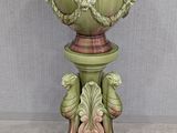 a green vase on a pedestal with a bird on it