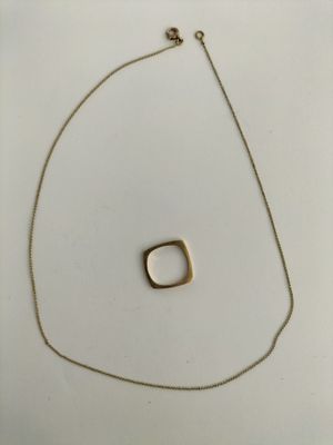 a close up of a gold necklace with a square pendant on it
