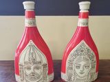 une paire de bouteilles rouges et blanches ornées de visages, posées sur une table en bois