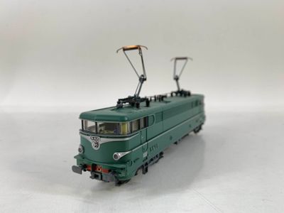 Le train vert est à l'arrêt sur les rails, sur la surface blanche.