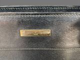 a close up of a black purse with a gold plate on it