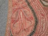 an orange and black paisley scarf laying on top of a gray floor