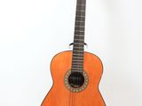 une guitare acoustique posée sur un support, adossée à un mur blanc