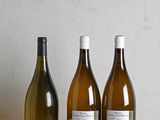 three bottles of wine are lined up on a wooden table