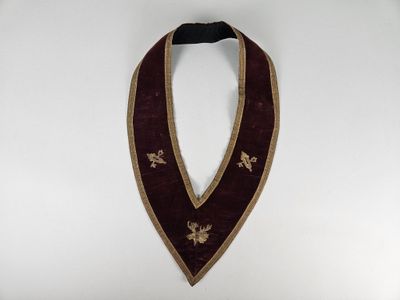 a close up of a red and gold collar on a white background