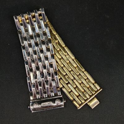 deux bracelets, l'un en argent et l'autre en or, posés sur un fond noir