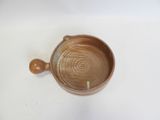 a brown bowl with a wooden handle on a white surface