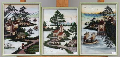 trois tableaux encadrés représentant des maisons et des bateaux, posés sur une étagère dans une pièce