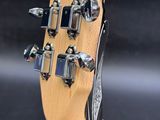 the headstock of an electric guitar with a wooden body and strings