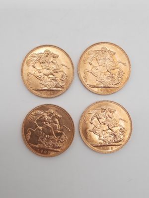 quatre types différents de pièces d'or reposant sur une surface blanche