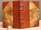 an old book with a golden cover sitting on top of a table
