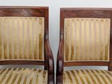 pair of wooden chairs with striped upholstered seats against a white wall