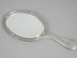 silver plated mirror with handle and handle on a gray surface