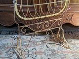 a small metal baby carriage on a rug in front of a wall