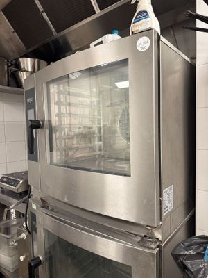des fours en acier inoxydable dans une cuisine professionnelle, avec des casseroles et des poêles posées sur le plan de travail