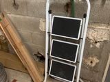 une échelle appuyée contre un mur, à côté d'un seau
