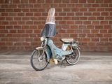 a small blue motorcycle parked in front of a brick wall