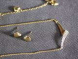 a gold necklace and earring set on a table