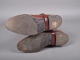 pair of brown leather shoes with red straps on a gray surface