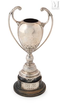 un trophée ancien en argent posé sur un socle en bois, sur fond blanc