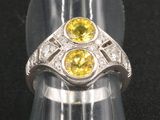 bague en argent ornée de pierres jaunes et blanches sur un fond noir