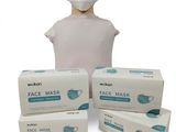 a person wearing a face mask next to three boxes of disposable face masks
