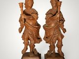 pair of carved wood figures of a man and a woman holding a torch