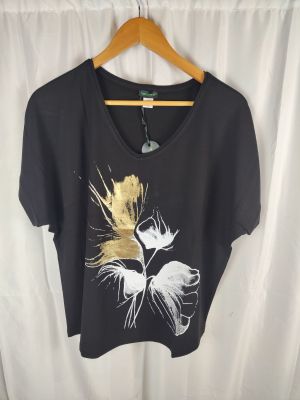 Le t-shirt est noir et doré, avec une fleur blanche dessus.