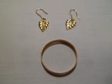 une bague en or et deux boucles d'oreilles en feuille d'or posées sur une table
