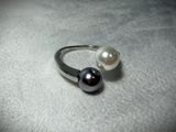 a ring with two pearls on it on a white surface