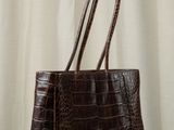 a brown crocodile skin tote bag on a wooden table